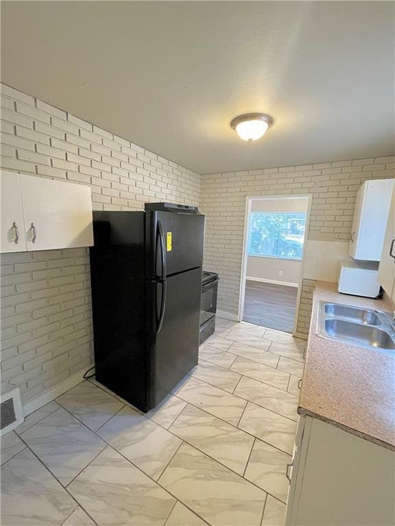 6645 Lydia Ave, Kansas City, MO 64131 - kitchen with light countertops, brick wall, marble finish floor, and freestanding refrigerator