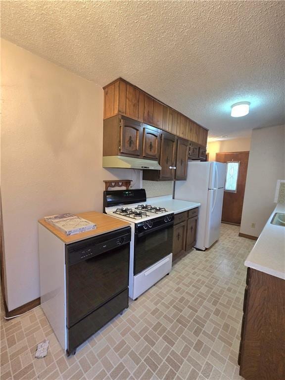 kitchen with light countertops, brick floor, under cabinet range hood, baseboards, and white appliances