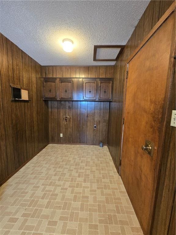 spare room featuring a textured ceiling, brick floor, and wood walls