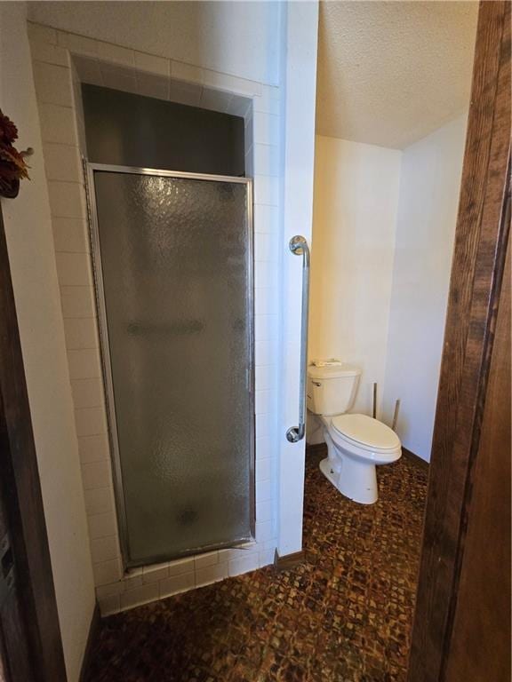 bathroom with a stall shower, toilet, and a textured ceiling