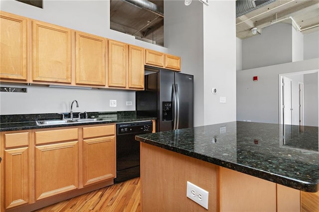 kitchen with light wood-style floors, fridge with ice dispenser, a sink, dark stone countertops, and dishwasher