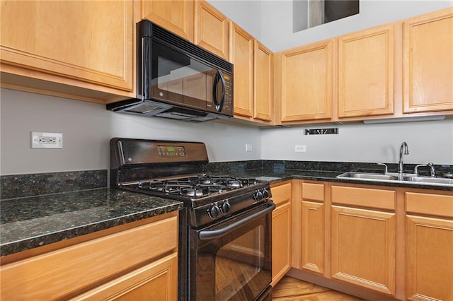 kitchen featuring dark stone counters, black appliances, and a sink