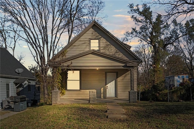 bungalow-style house featuring a lawn and covered porch