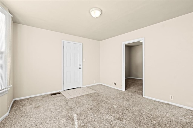 unfurnished room with visible vents, baseboards, and carpet floors