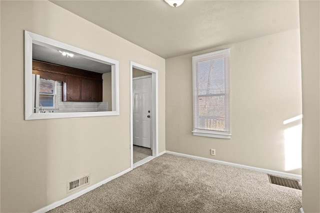 empty room with visible vents, baseboards, and carpet flooring