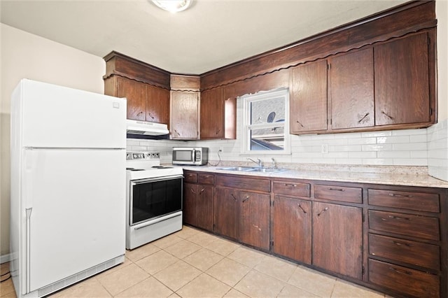 kitchen with under cabinet range hood, white appliances, light countertops, and a sink