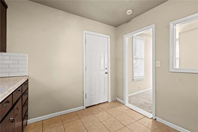 interior space with dark brown cabinetry, light tile patterned floors, and baseboards