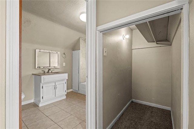 bathroom with baseboards, vaulted ceiling, a bath, tile patterned floors, and vanity