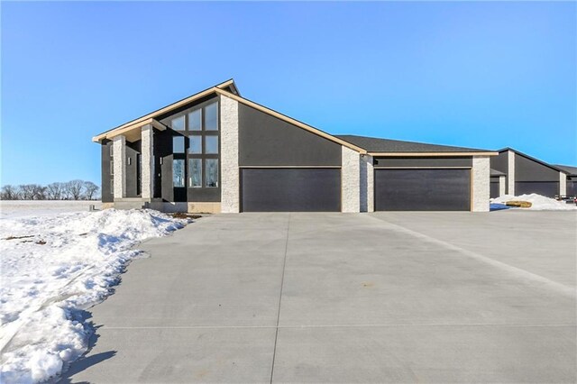 view of front of house with stone siding, a garage, and driveway