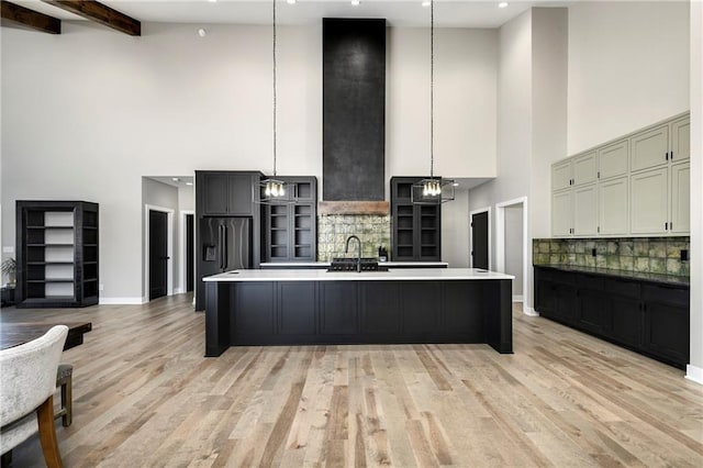 kitchen featuring light wood-type flooring, a sink, tasteful backsplash, a spacious island, and high end refrigerator