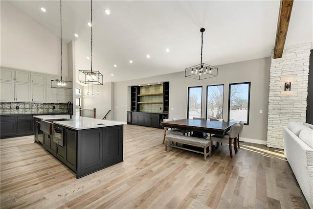 kitchen featuring light wood finished floors, high vaulted ceiling, light countertops, decorative light fixtures, and open floor plan