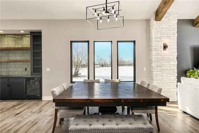 dining space featuring wine cooler, plenty of natural light, beamed ceiling, and light wood finished floors