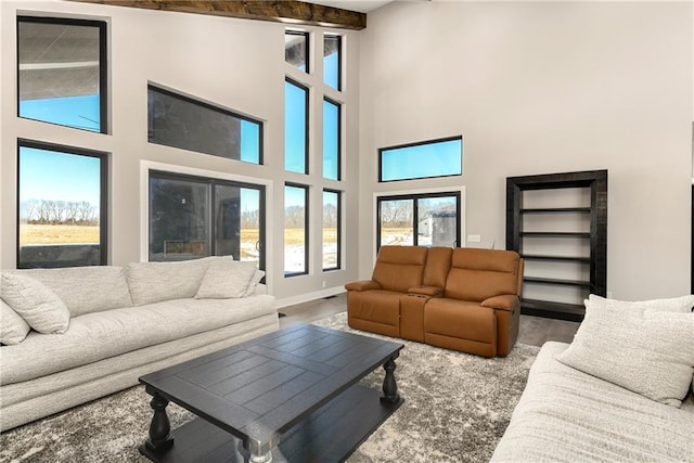 living room featuring a high ceiling, baseboards, and wood finished floors