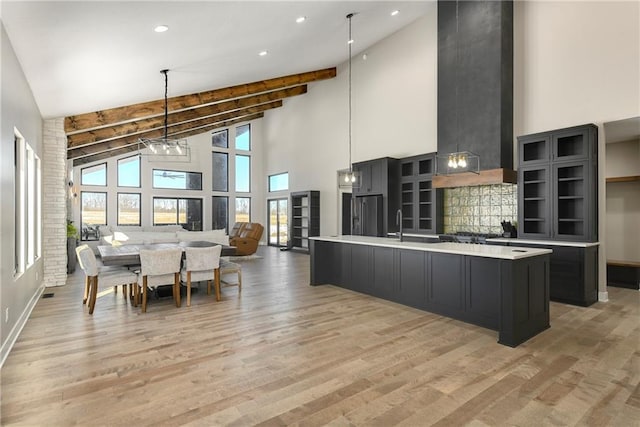 kitchen with light countertops, light wood-style flooring, stainless steel fridge with ice dispenser, and dark cabinets