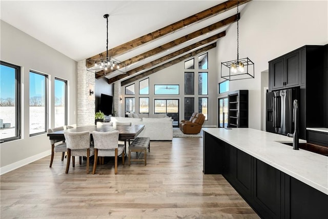 dining space with beamed ceiling, a notable chandelier, high vaulted ceiling, and light wood finished floors