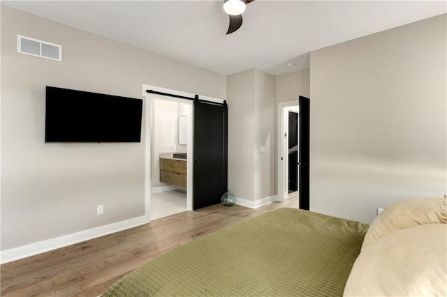 unfurnished bedroom featuring a barn door, baseboards, visible vents, and light wood-type flooring