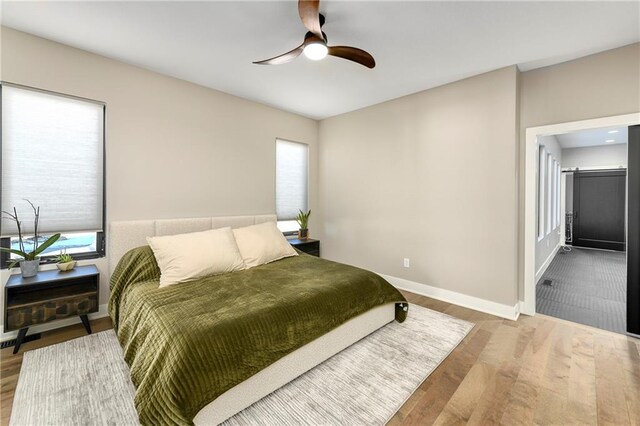 bedroom with a ceiling fan, baseboards, and wood finished floors