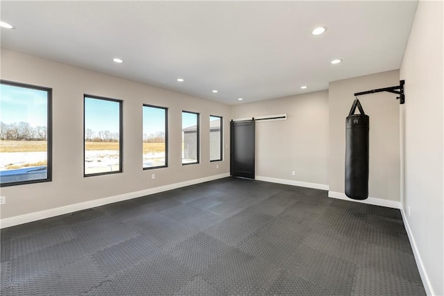 empty room featuring a barn door, recessed lighting, and baseboards