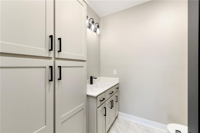 bathroom with marble finish floor, toilet, vanity, and baseboards