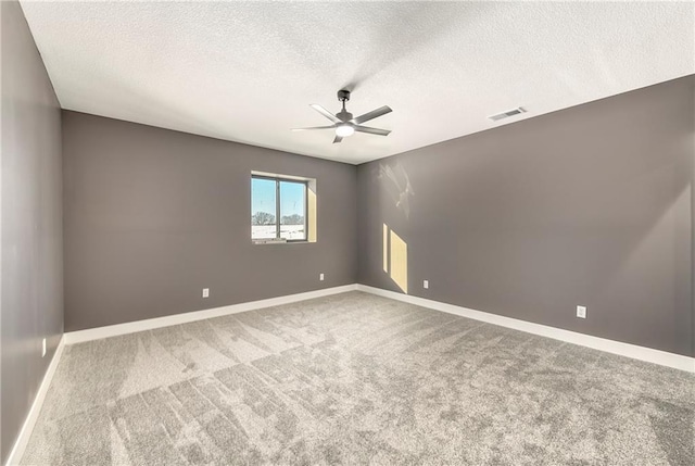 carpeted spare room with visible vents, ceiling fan, and baseboards