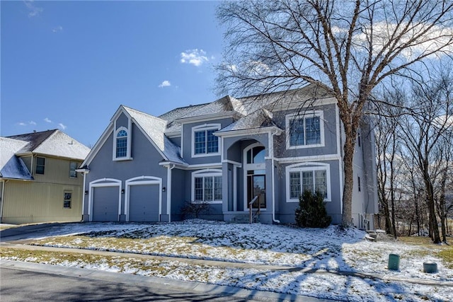 traditional-style house with a garage, driveway, and stucco siding