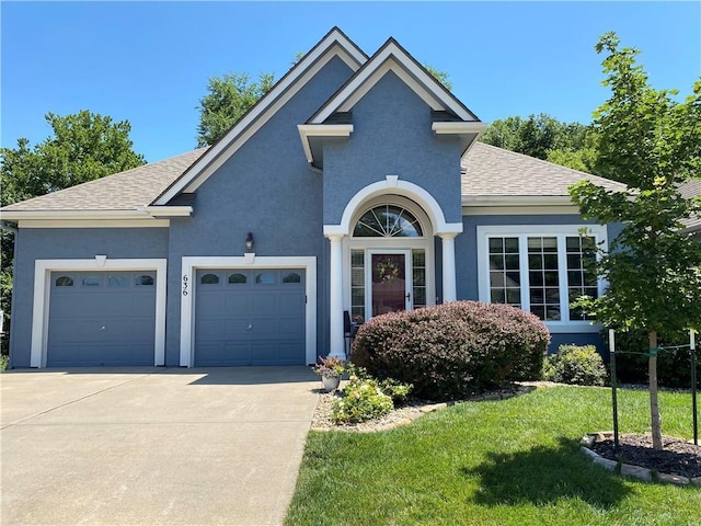 view of front of home with a garage, a shingled roof, concrete driveway, a front lawn, and stucco siding