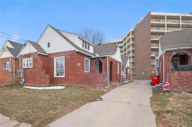 view of home's exterior with roof with shingles and brick siding