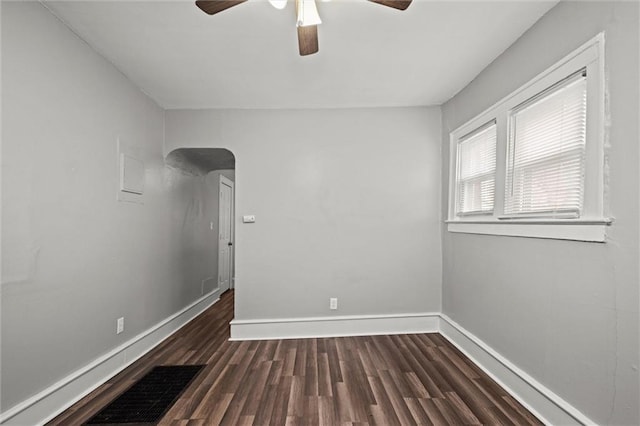 spare room featuring a ceiling fan, dark wood-style flooring, visible vents, and baseboards