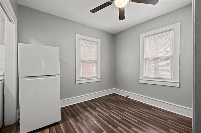 spare room with dark wood-style floors, a healthy amount of sunlight, baseboards, and a ceiling fan