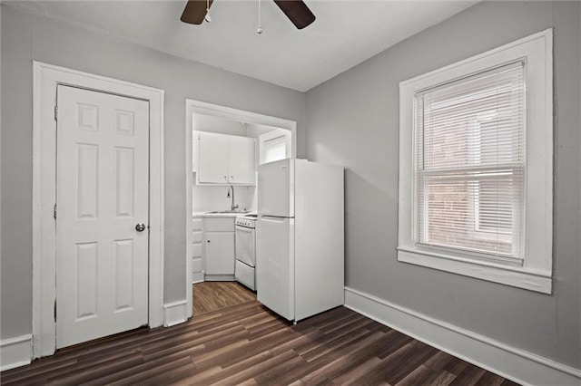 unfurnished bedroom with dark wood-type flooring, a sink, freestanding refrigerator, and baseboards