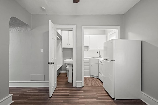 interior space featuring dark wood-style floors, a sink, freestanding refrigerator, and white cabinets