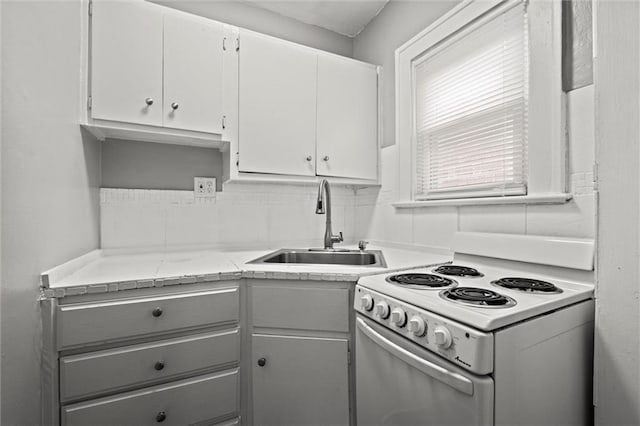 kitchen featuring light countertops, backsplash, electric range, white cabinetry, and a sink