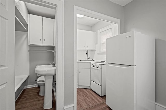 kitchen with dark wood-type flooring, white appliances, white cabinets, and a sink