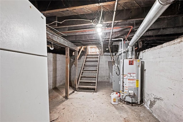 unfinished below grade area featuring freestanding refrigerator, gas water heater, and stairs