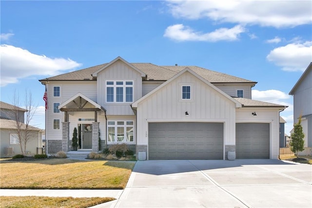 view of front facade featuring a front yard, stone siding, board and batten siding, and driveway