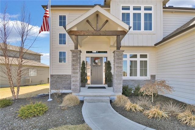 doorway to property with board and batten siding and stone siding