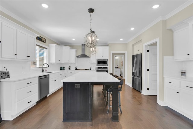 kitchen featuring a center island, ornamental molding, a kitchen breakfast bar, stainless steel appliances, and wall chimney exhaust hood