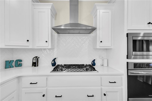 kitchen featuring white cabinetry, wall chimney exhaust hood, tasteful backsplash, and stainless steel appliances