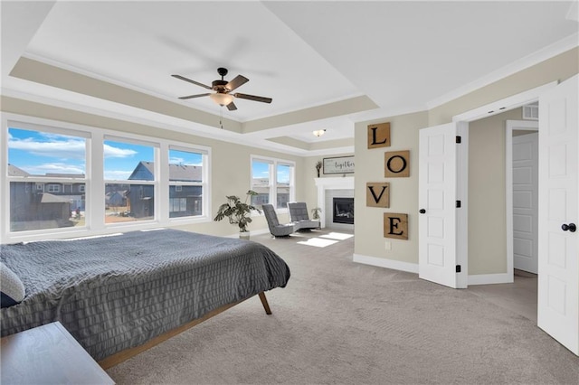 bedroom with a tray ceiling, a fireplace, carpet flooring, crown molding, and baseboards