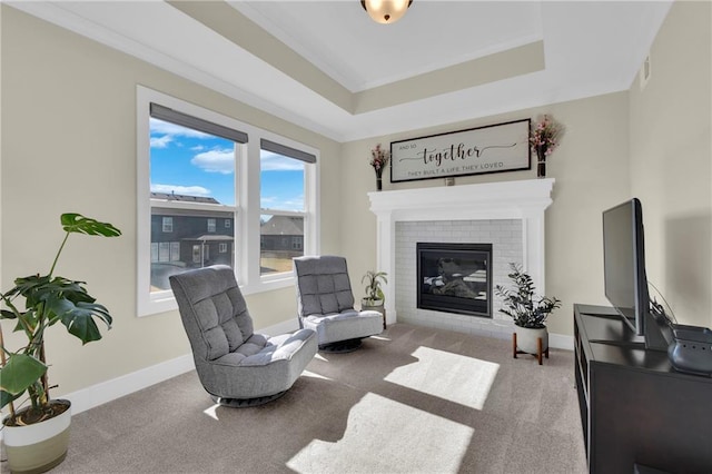 sitting room featuring visible vents, a tray ceiling, carpet flooring, baseboards, and a brick fireplace