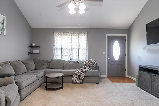 carpeted living area featuring baseboards, lofted ceiling, and a ceiling fan