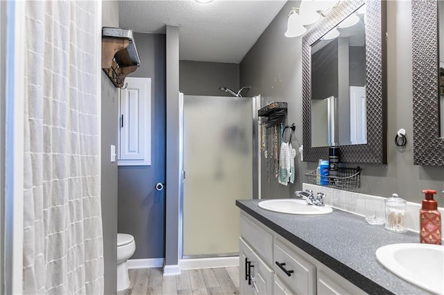 bathroom with wood finished floors, a stall shower, a textured ceiling, and a sink