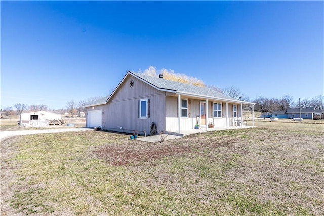 single story home with a front yard, an attached garage, covered porch, and driveway