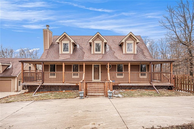 view of front of property with covered porch, driveway, a chimney, and fence