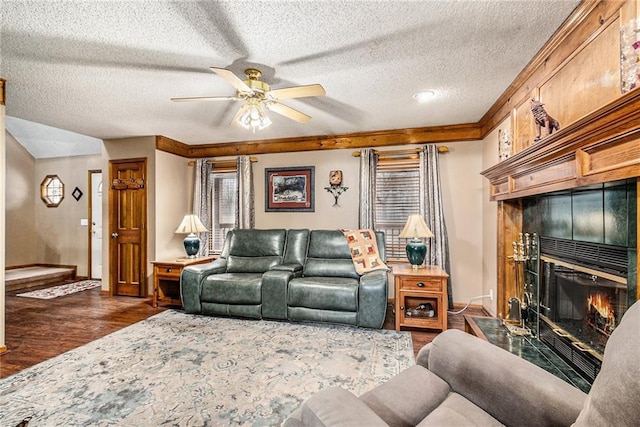 living area with wood finished floors, plenty of natural light, a fireplace, and ceiling fan