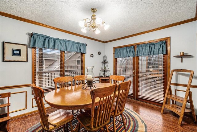 dining area featuring wood finished floors, a textured ceiling, a chandelier, and crown molding