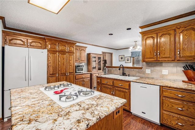 kitchen with dark wood finished floors, white appliances, brown cabinets, and a sink