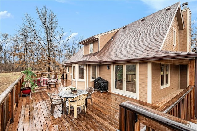 wooden terrace featuring outdoor dining area, french doors, and a grill