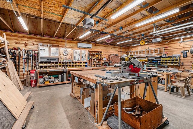 miscellaneous room featuring a workshop area, an AC wall unit, and concrete floors