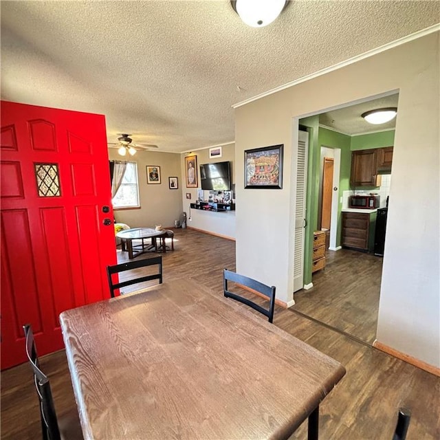 dining space with ceiling fan, a textured ceiling, dark wood-style flooring, baseboards, and crown molding